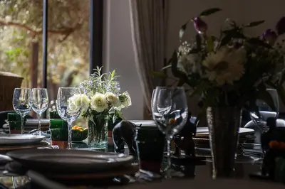 a table with glasses and a vase of flowers on it at Dar Toozween in Marrakech