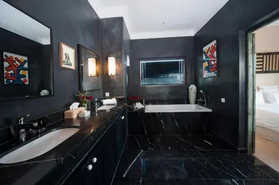 a black bathroom with a sink and a tub at Dar Toozween in Marrakech