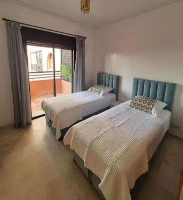 two beds in a room with a window at Comfortable poolside apartment near city center in Marrakech