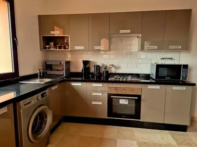 a kitchen with a stove and a washer and sink at Comfortable poolside apartment near city center in Marrakech