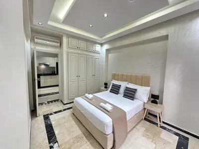 a bedroom with a large white bed and a kitchen at Elegant Suit in Guéliz in Marrakech