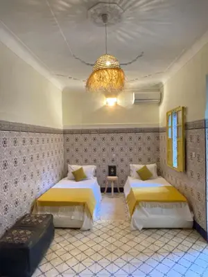 a bedroom with two beds and a chandelier at Khamsa in Marrakech