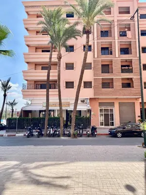 a large pink building with palm trees in front of it at Very comfortable apartment in a perfect location in Marrakech