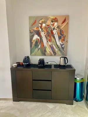 a painting hanging on a wall above a wooden cabinet at Very comfortable apartment in a perfect location in Marrakech