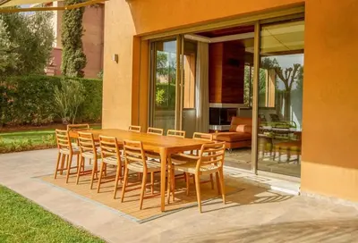 a wooden table and chairs in front of a house at Villa Dar Saliha in Ala el Ma