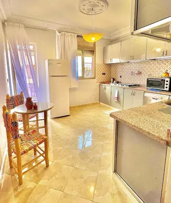 a kitchen with a table and a refrigerator at Marrakech in Marrakech