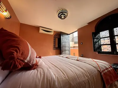 a bedroom with a large bed with orange walls at Charming private riad with pool in Marrakech
