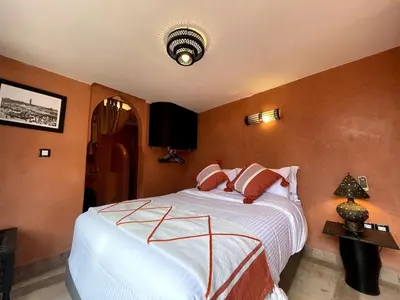 a bedroom with a large bed with orange walls at Charming private riad with pool in Marrakech