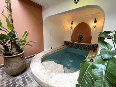 a large pool in a room with a large plant at Charming private riad with pool in Marrakech