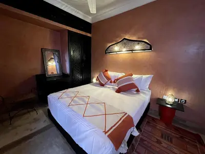 a bedroom with a bed with white sheets and orange pillows at Charming private riad with pool in Marrakech
