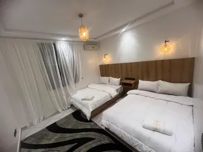 a hotel room with two beds and two windows at Cozy appartement au centre de marrakech in Marrakech