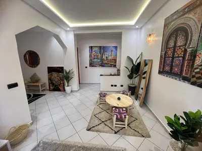 a living room with a table and some paintings on the wall at Cozy appartement au centre de marrakech in Marrakech