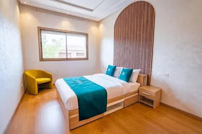 a bedroom with a large bed and a yellow chair at Petit Palm in El Rhechat