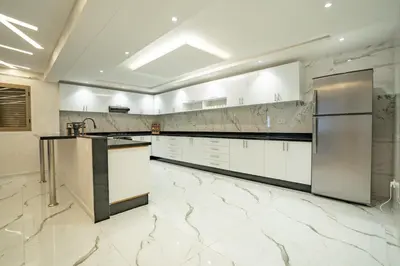 a large kitchen with white appliances and marble floors at Petit Palm in El Rhechat