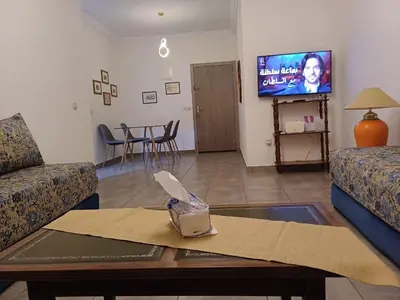 a living room with a table and a tv at Cosy 2-bedroom apt in Ourika Route in Marrakech