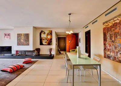 a living room with a dining table and a living room with a painting at Apartment with Private Rooftop & Jaccuzzi in Marrakech