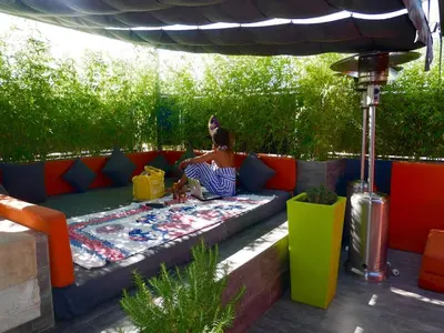 a woman sitting on a couch under an umbrella at Apartment with Private Rooftop & Jaccuzzi in Marrakech