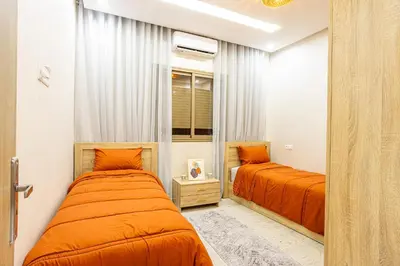 two beds in a bedroom with orange sheets at HAGS Apartment - Traditional Modern Apartment, full AC, 10m from airport in Marrakech