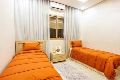 two beds in a room with orange sheets at HAGS Apartment - Traditional Modern Apartment, full AC, 10m from airport in Marrakech