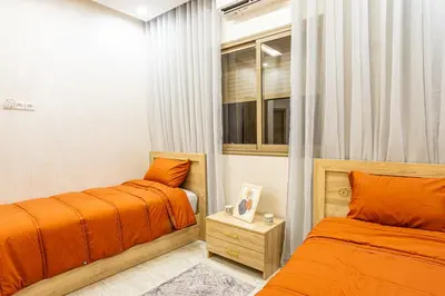 two beds in a small room with orange sheets at HAGS Apartment - Traditional Modern Apartment, full AC, 10m from airport in Marrakech