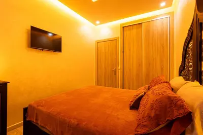 a bedroom with a bed and a television on the wall at HAGS Apartment - Traditional Modern Apartment, full AC, 10m from airport in Marrakech