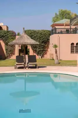 two chairs and an umbrella in front of a house at Résidence AYDA Riad Villa Hanane in Marrakech