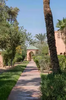 a walking path with a building and a palm tree at Résidence AYDA Riad Villa Hanane in Marrakech