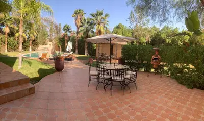 a patio with a table and chairs and an umbrella at Villa Palmeraire Marrakech, Private pool, Private Hamam in Marrakech