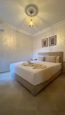 a bedroom with a large white bed with a ceiling at La perle d'atlas appartement in Marrakech