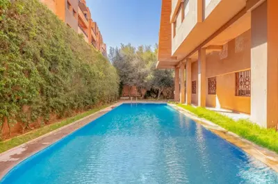 a blue swimming pool between two buildings at Elegant 2-BR, Pool And Parking Hivernage Centre in Marrakech
