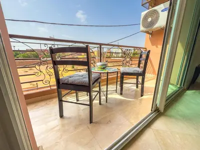 a balcony with two chairs and a table on a balcony at Elegant 2-BR, Pool And Parking Hivernage Centre in Marrakech