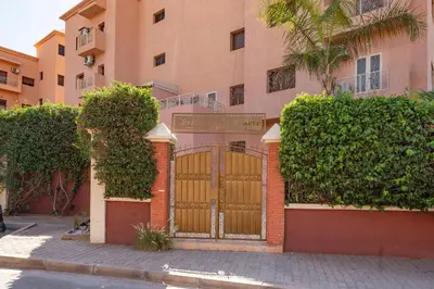 a gate in front of a building with bushes at L'essentiel au soleil piscine parking in Marrakech