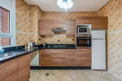 a kitchen with wooden cabinets and a white refrigerator at L'essentiel au soleil piscine parking in Marrakech