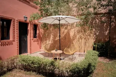 two chairs and a table with an umbrella on a patio at Villa Marrakchia - Palais d'hôtes in Marrakech
