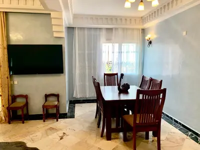a dining room with a table and chairs and a television at Appartement Gueliz in Marrakech
