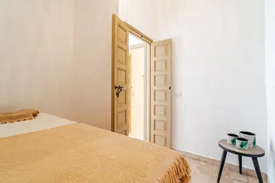 a bedroom with a bed and a table and a door at Riad Dar Tonka in Marrakech
