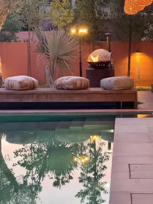a swimming pool with a fire place in a backyard at Imagine Villa in Marrakech