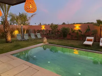 a swimming pool in a yard with chairs and a house at Imagine Villa in Marrakech