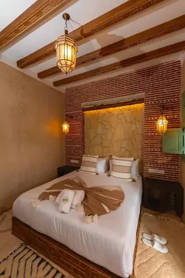 a bedroom with a large bed with a brick wall at Riad DAR ELMA NOI in Marrakech