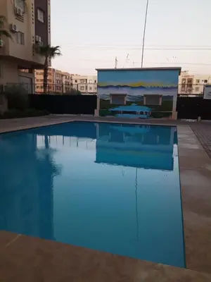 a large blue swimming pool in front of a building at Logement Confort Résidence Fermée avec Piscine in Marrakech