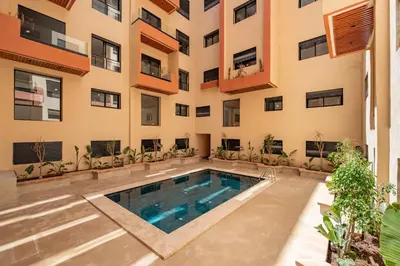 an apartment with a swimming pool in front of a building at Modern Studio in Hivernage with Pool Access in Marrakech