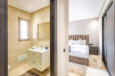 a bedroom with a bed and a bathroom with a sink at Spacious luxury 3BR by the pool in Marrakech