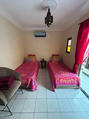 two beds in a room with red sheets and a couch at Riad Marrakech in Marrakech