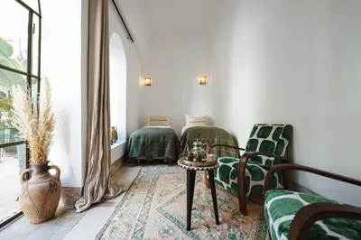 two beds in a room with green chairs and a table at Nahla Wellness in Marrakech