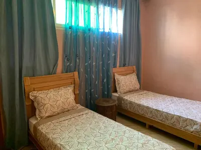 a bedroom with two beds and a window with curtains at Appartement Marrakechi in Marrakech
