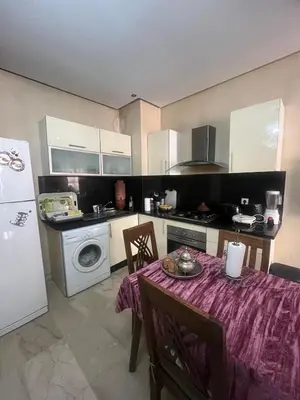 a small kitchen with a table and a refrigerator at nice apartment and good location in Marrakech