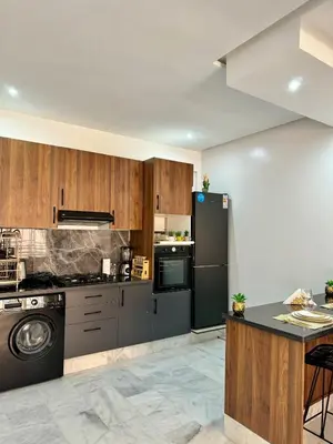 a kitchen with wooden cabinets and a black refrigerator at Cocoon in Gueliz, Netflix, IPTV in Marrakech