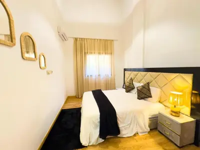 a bedroom with a white bed with a black and yellow headboard at Cozy apartment with a pool2 in Marrakech