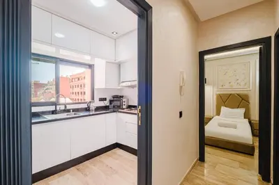a kitchen with white cabinets and a sink and a bed at Cozy Appartement in the heart of Gueliz Marrakech in Marrakech
