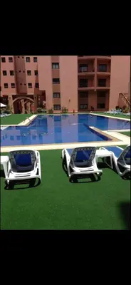 two chairs sitting on the grass near a swimming pool at Big confort in Marrakech